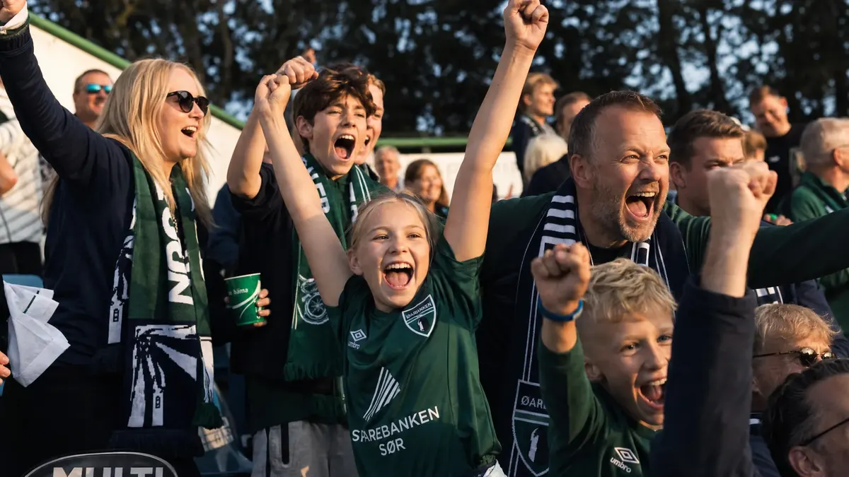 Supportere i klubbfarger jubler på tribunen
